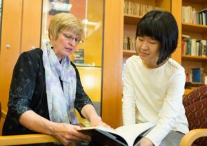 Danhui Zhang ’18 and Margerete Lamb-Faffelberger look at a book together.