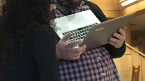 John Boyer holds a laptop while talking with student debate competitor Vanessa Milan '16