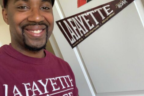 Tim Cox wearing a Lafayette shirt near a Lafayette pennant and image of the Marquis de Lafayette