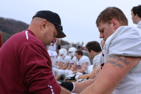 Matt Bayly tapes up a football player on the sidelines.