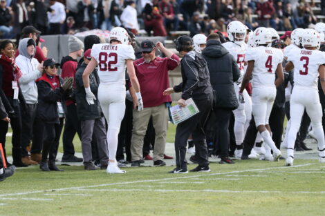Matt Bayly, director of sports medicine and head athletics trainer, stands on the sidelines between a player and football head coach John Garrett.