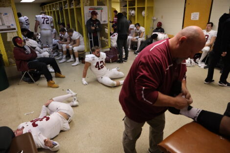 Matt Bayly tapes a football player's ankle in the lockerroom.