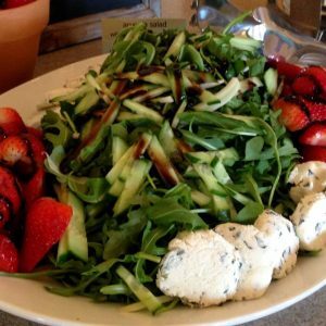 Greens, cheese, and strawberries on a plate