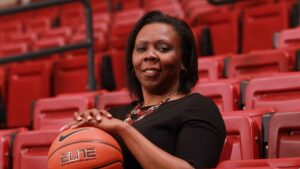 Women's basketball head coach Kia Damon-Olson with her hands on a basketball in Kirby Sports Center