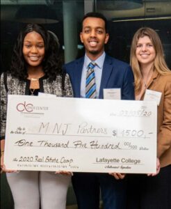 Three students hold an oversized check, the prize for the Real Estate Case Competition