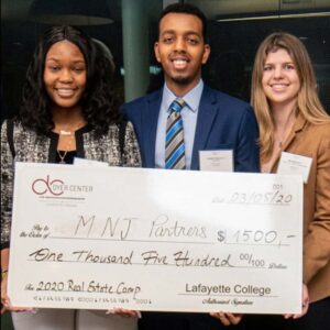 Three students hold an oversized check, the prize for the Real Estate Case Competition