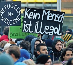 A crowd, some people carrying signs, at a pro-refugee rally in Germany