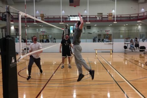 A student jumps up to spike the volleyball in an intramural match.