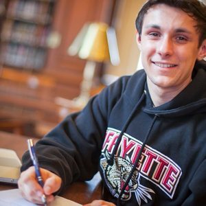 A student wearing a Lafayette sweatshirt with a pen in hand