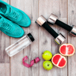 A pair of hand weights, a pair of aqua running shoes, a water bottle, two pears, and a split grapefruit