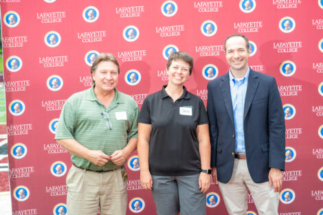 Jenn Dize and two male employees pose in front of the Lafayette-branded backdrop at the conclusion of the faculty-staff awards event at Fisher Stadium