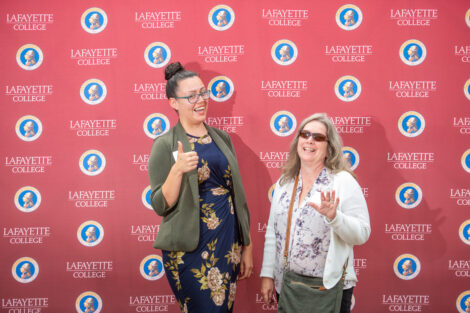 Two female employees pose in front of the Lafayette-branded backdrop at the conclusion of the faculty-staff awards event at Fisher Stadium
