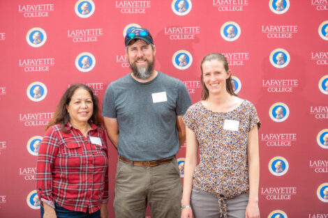 John Wilson and two female employees pose in front of the Lafayette-branded backdrop at the conclusion of the faculty-staff awards event at Fisher Stadium