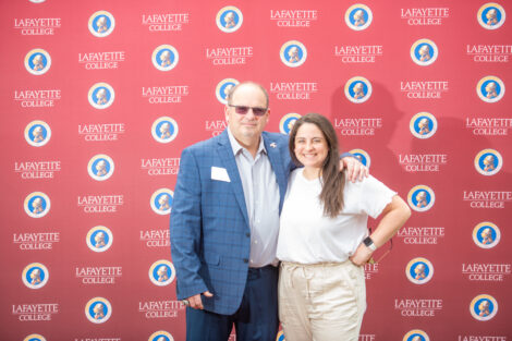 Two employees pose in front of the Lafayette-branded backdrop at the conclusion of the faculty-staff awards event at Fisher Stadium