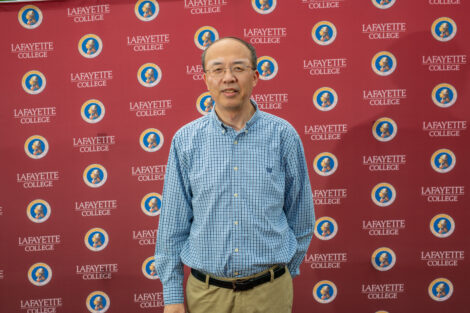 A male employees poses in front of the Lafayette-branded backdrop at the conclusion of the faculty-staff awards event at Fisher Stadium