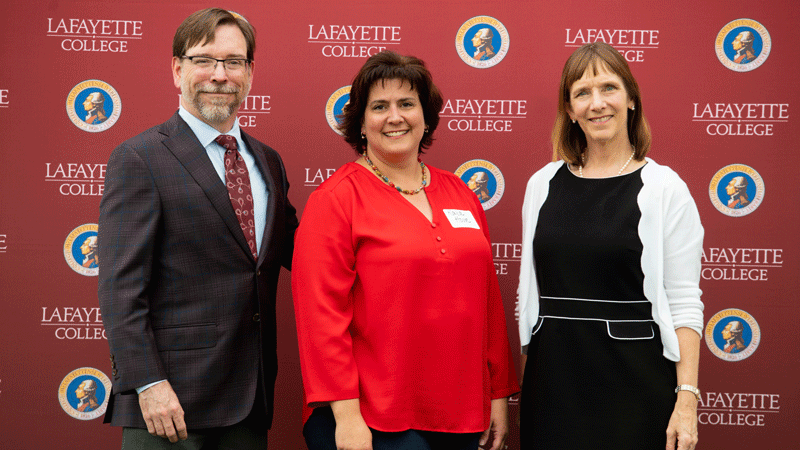 Kara Howe stands flanked by Provost John Meier and President Alison Byerly in front of a Lafayette-branded backdrop at Fisher Stadium.