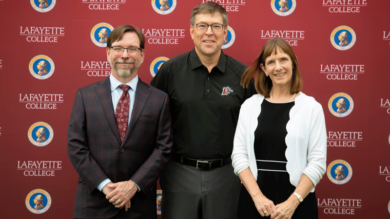 Scott Morse stands flanked by Provost John Meier and President Alison Byerly in front of a Lafayette-branded backdrop at Fisher Stadium.