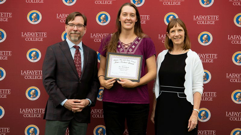 Zoe Boekelheide holds her award while flanked by Provost John Meier and President Alison Byerly in front of a Lafayette-branded backdrop at Fisher Stadium.