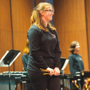 Anna Zittle holds mallets and smiles on stage during the Percussion Ensemble concert.