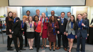 A group photo of the student Forensics Society, with two in the middle holding a trophy up together