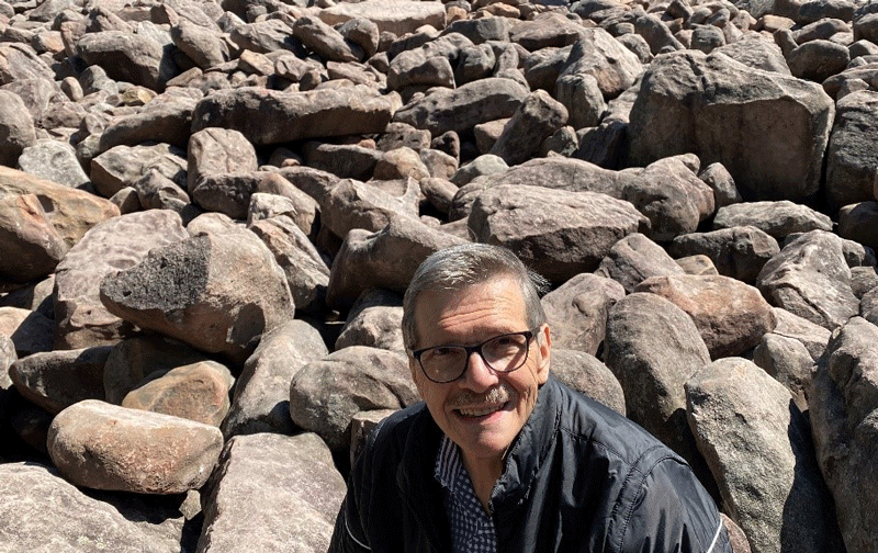 Larry Stockton in front a large pile of rocks