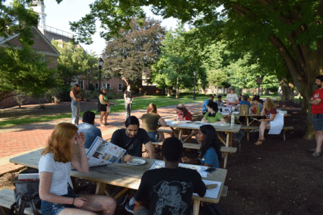Students and staff at several picnic tables near the Quad create paintings of cacti.
