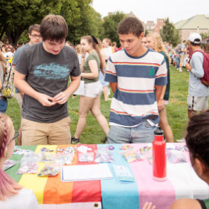 Two students stand at an organization's table at the Student Involvement Fair on the Quad.
