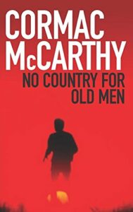 The cover of No Country for Old Men, with a bred background and a view from behind of man walking with a yellow orb by his feet
