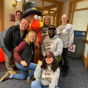 Seven members of Campus Life pose for a group photo by the plastic Tom the Turkey in Farinon.