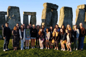 Two Lafayette professors and their group of students pose for a photo in front of Stonehenge.
