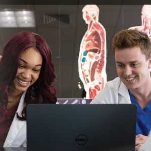 Two medical students look at a computer screen together.