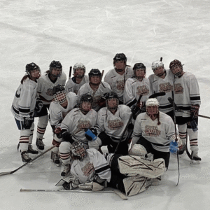Members of the women's club ice hockey team in uniform and with equipment on the rink for a group photo