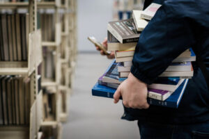 A person carrying a stack of books in the library.