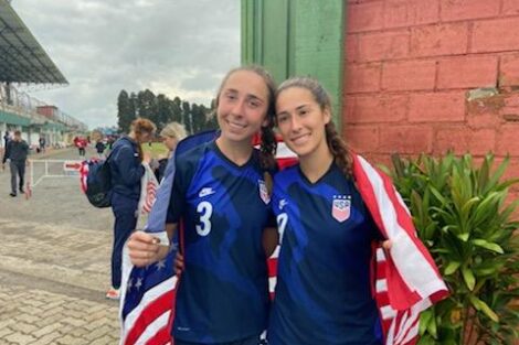 Ani Khachadourian '25 poses with a teammate, both wrapped in a U.S. flag