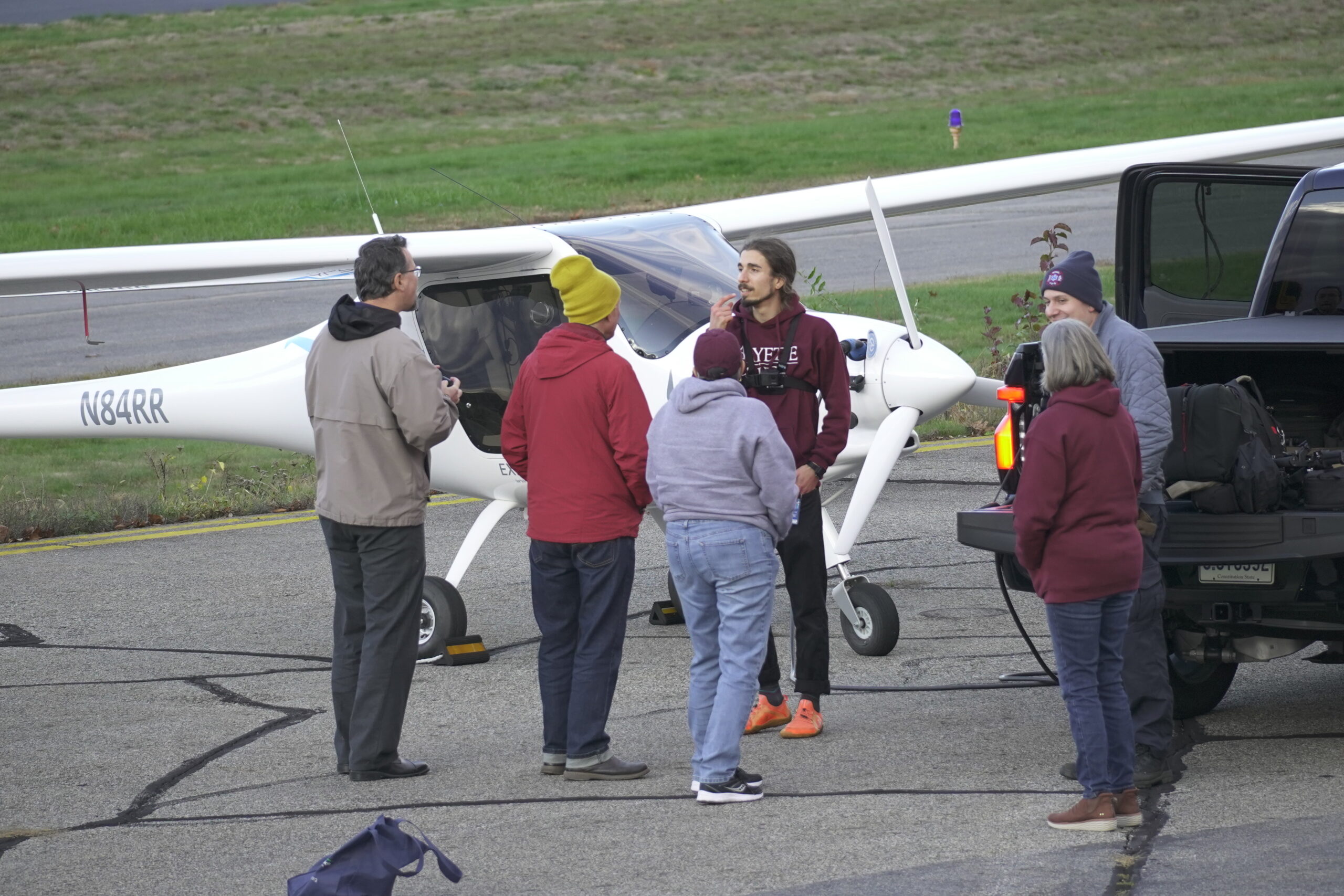 A group from Lafayette stands near an electric plane on the runway.