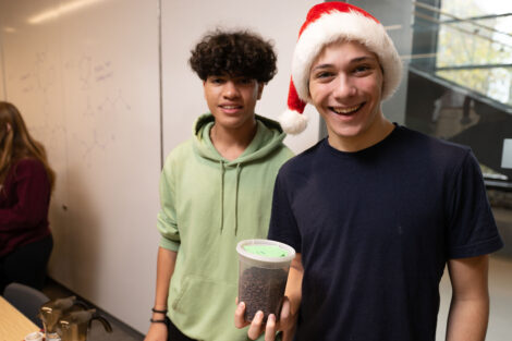 Two students hold up their signature blend of coffee Professor Joseph Woo’s FYS143 Coffee Showcase.