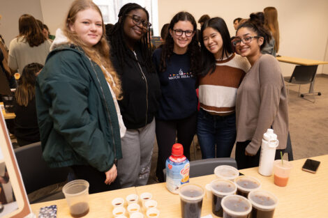 A group of students stands by their final coffee project in Professor Joseph Woo’s FYS143 Coffee Showcase.