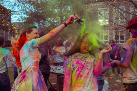 Students dump colorful powder on each other during Holi Fest.