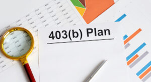 a magnifying class sits on a pile of documents with text 403(b) Plan