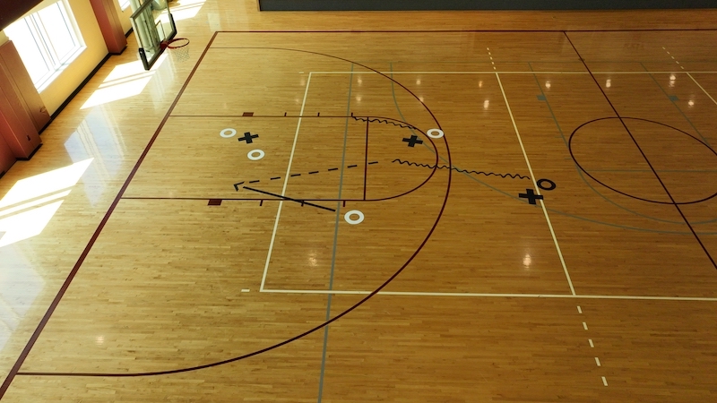 Taliyah Medina sketches image on basketball court, making the surface look like a coach's play drawing clipboard.