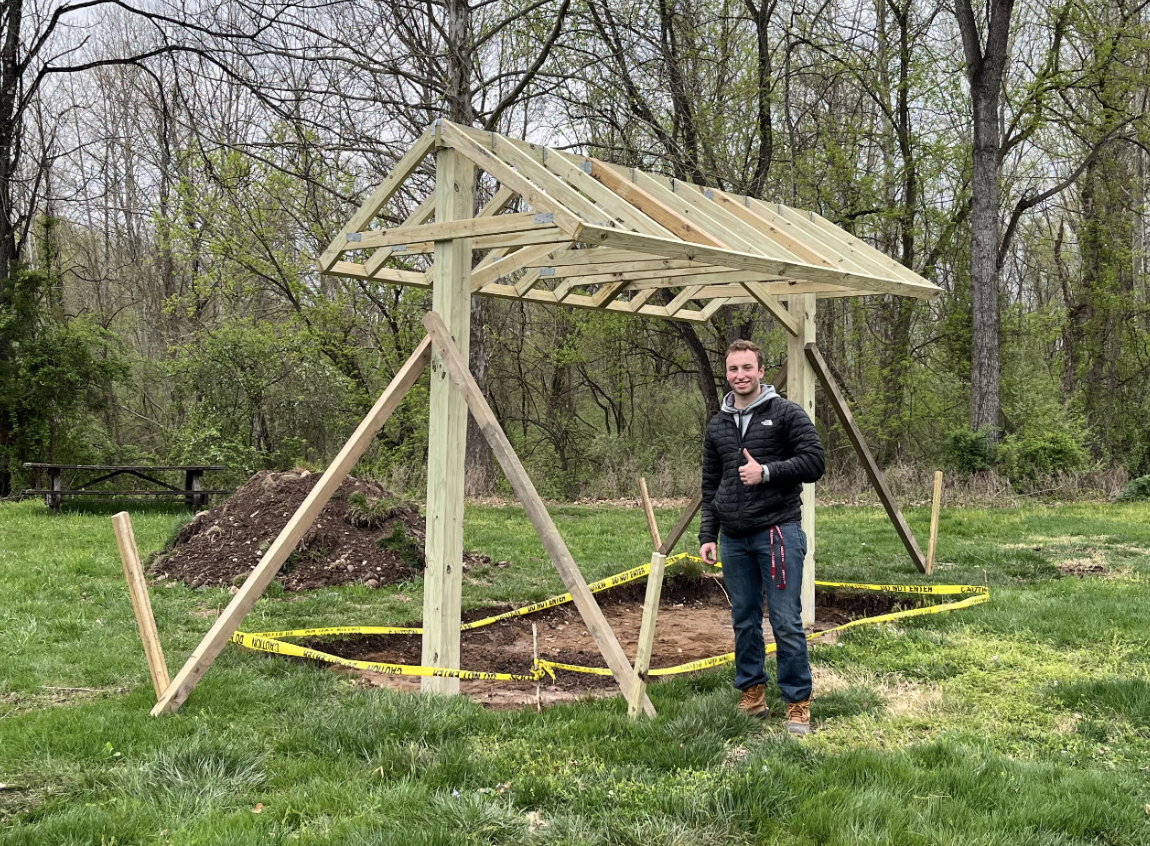 A student with Engineers without Borders stands near the frame of the picnic table canopy for Delaware Canal State Park in Upper Black Eddy, Pa.