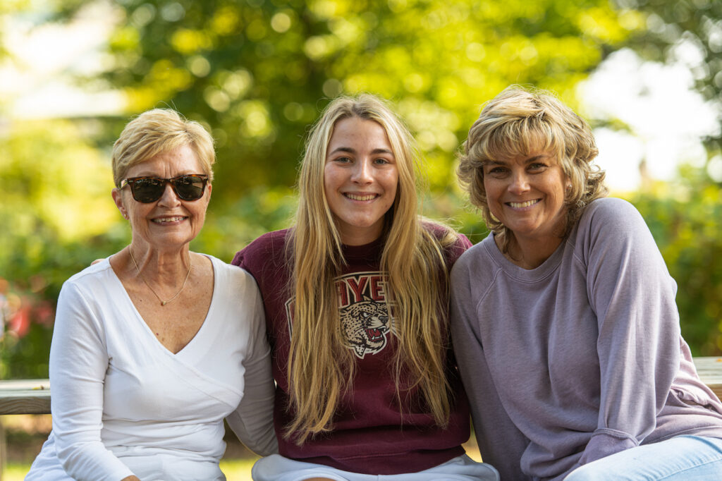 A Laf student stands with two female family members.