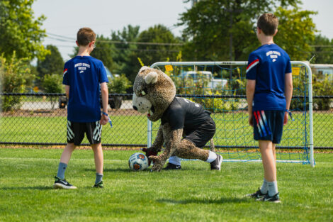 The leopard saves a ball from going into the goal as two young boys watch at Gummeson Grounds Community Day