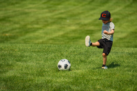 A young fan in a Lafayette hat kicks a ball at Gummeson Grounds