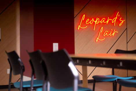 Photos of the new Leopard's Lair in Farinon. Neon sign saying Leopard's Lair is displayed on the wall, with colorful chairs spread throughout the room.