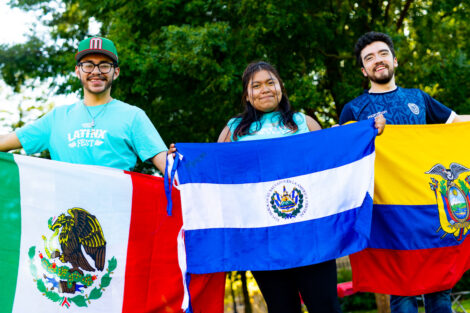 Three students hold international flags during Latinx Fest.