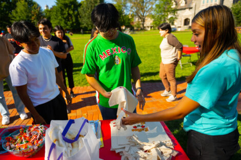 A student picks up a tote bag during LAtinx FEst