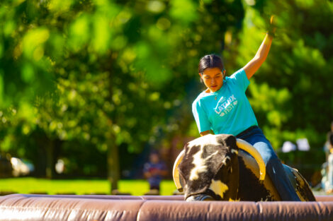 A girl rides a mechanical bull during Latinx Fest