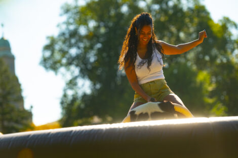 A girl rides a mechanical bull during Latinx Fest.