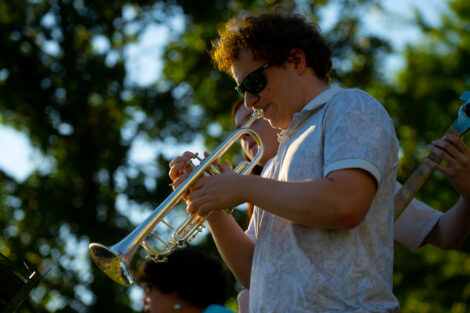 A student plays a trumpet on the Quad.